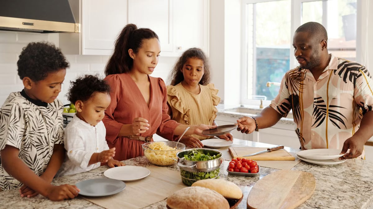 A family shares a joyful meal preparation in a bright, modern kitchen setting.